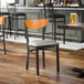 A black metal chair with a light gray vinyl seat and a cherry wood curved backrest.