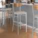 Lancaster Table & Seating Boomerang Series bar stools with wooden and vinyl seats and vintage wood backs.