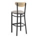 A black Lancaster Table & Seating bar stool with a light gray cushioned seat and driftwood back.