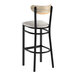 A bar stool with a black metal frame, light gray vinyl seat, and a driftwood-finished curved wooden backrest.