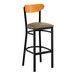 A bar stool with a black metal frame, taupe vinyl seat, and a cherry wood backrest.