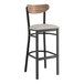 A Lancaster Table & Seating bar stool with a black frame, light gray vinyl seat, and vintage wood back.