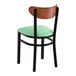 A black metal chair with a seafoam vinyl seat and an antique walnut wood backrest.