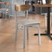 A Lancaster Table & Seating Boomerang Series wood and metal chair with a light gray cushion in a restaurant.