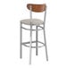 A Lancaster Table & Seating bar stool with a light gray cushion and wooden back.