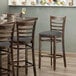 A Lancaster Table & Seating vintage wood ladder back bar stool with dark gray vinyl seat detached.