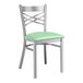 A Lancaster Table & Seating metal cross back chair with a seafoam green cushion.