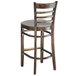 A Lancaster Table & Seating wooden bar stool with a light grey cushion.