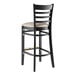 A black wood bar stool with a light gray cushion on the seat.