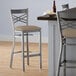 A Lancaster Table & Seating clear coat finish cross back bar stool with a taupe vinyl padded seat.