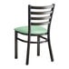 A black Lancaster Table & Seating ladder back chair with a seafoam green vinyl padded seat.