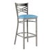 A Lancaster Table & Seating metal bar stool with a blue vinyl padded seat.