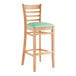 A Lancaster Table & Seating wooden bar stool with a seafoam green vinyl seat.