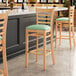 A Lancaster Table & Seating wood ladder back bar stool with a detached seafoam vinyl seat.