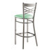 A Lancaster Table & Seating metal bar stool with a seafoam green padded seat.