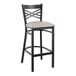 A black metal Lancaster Table & Seating bar stool with a light gray cushion.