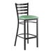 A black metal bar stool with a ladder back and a seafoam green vinyl padded seat.