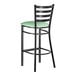 A black metal bar stool with a ladder back design and a seafoam green vinyl padded seat.