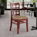 A Lancaster Table & Seating wooden chair with a taupe vinyl seat in a restaurant.