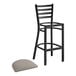 A Lancaster Table & Seating black ladder back bar stool with a dark gray cushion.