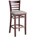 A Lancaster Table & Seating wooden bar stool with a light gray cushion on the seat.