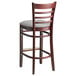 A Lancaster Table & Seating mahogany wood bar stool with a light gray vinyl cushion and ladder back.