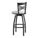 A black metal swivel bar stool with a cross back design and a light gray vinyl padded seat.