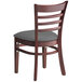 A Lancaster Table & Seating wooden chair with a dark gray cushion on the seat and a ladder back.