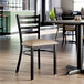 A ladder back chair with a distressed copper finish and a taupe vinyl padded seat.