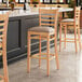 A Lancaster Table & Seating wooden ladder back bar stool with a taupe vinyl seat.
