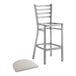 A Lancaster Table & Seating metal ladder back bar stool with a light gray cushion on the seat