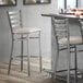 A Lancaster Table & Seating clear coat finish ladder back bar stool with a light gray vinyl padded seat.