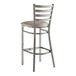 A Lancaster Table & Seating metal ladder back bar stool with a light gray cushion on the seat.