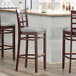 Three Lancaster Table & Seating mahogany wood bar stools with light gray vinyl window backs and seats.