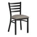 A black Lancaster Table & Seating ladder back chair with a dark gray vinyl padded seat.