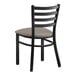 A black metal Lancaster Table & Seating ladder back chair with a dark gray vinyl padded seat.