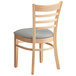 A Lancaster Table & Seating wooden restaurant chair with a light grey vinyl cushion.