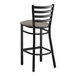 A Lancaster Table & Seating black ladder back bar stool with a dark gray cushion.