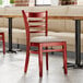 A Lancaster Table & Seating mahogany wood chair with a light gray vinyl seat detached.