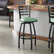 A black metal ladder back swivel bar stool with a 2 1/2-inch seafoam green vinyl padded seat.