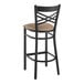 A Lancaster Table & Seating black cross back bar stool with taupe vinyl padded seat.