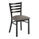 A metal ladder back chair with a distressed copper finish and a dark gray vinyl padded seat.