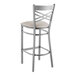 A Lancaster Table & Seating metal cross back bar stool with a light gray cushion.