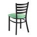 A black ladder back chair with a seafoam green vinyl padded seat.