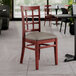 A Lancaster Table & Seating mahogany wood chair with a dark gray vinyl seat.