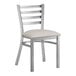 A Lancaster Table & Seating metal ladder back chair with a light gray vinyl padded seat.