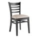 A black Lancaster Table & Seating wood chair with a light gray vinyl seat.