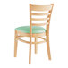 A Lancaster Table & Seating wooden chair with a seafoam vinyl cushion and ladder back.