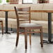 A Lancaster Table & Seating wooden chair with a dark gray vinyl seat.