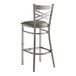 A Lancaster Table & Seating silver metal cross back bar stool with a dark gray cushion.